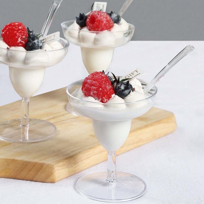 Delicious dessert cups with whipped cream, raspberries, and blueberries on a wooden board.