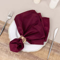 Burgundy fabric napkin elegantly styled on a white plate with cutlery.