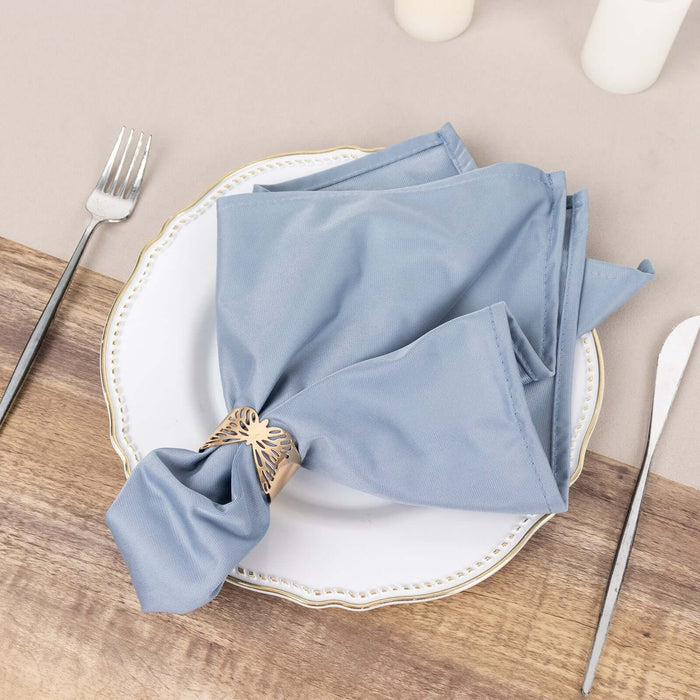 Elegant blue napkin tied with a decorative ring on a white plate.