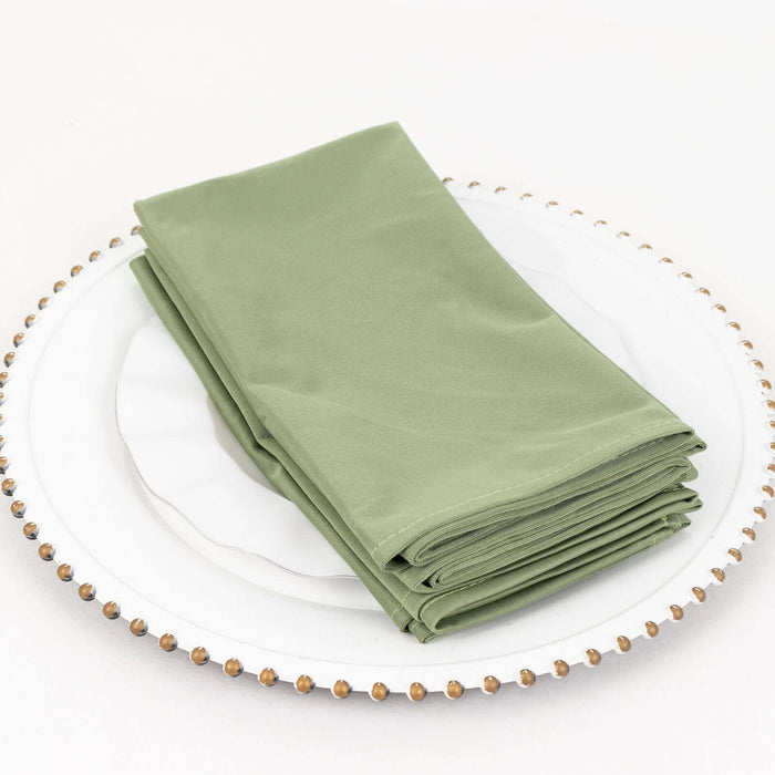 Set of four elegant green napkins neatly stacked on a decorative plate.