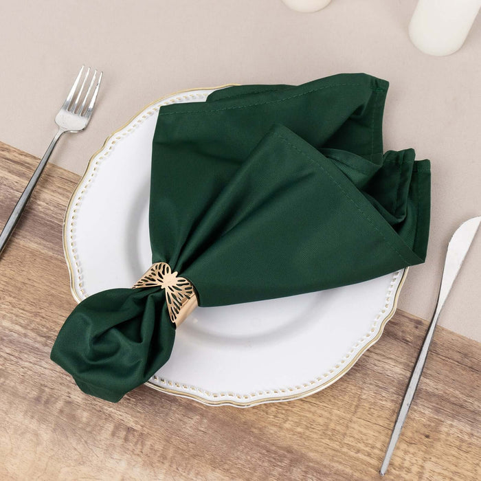 Green napkin elegantly tied with a decorative ring on a decorative plate.