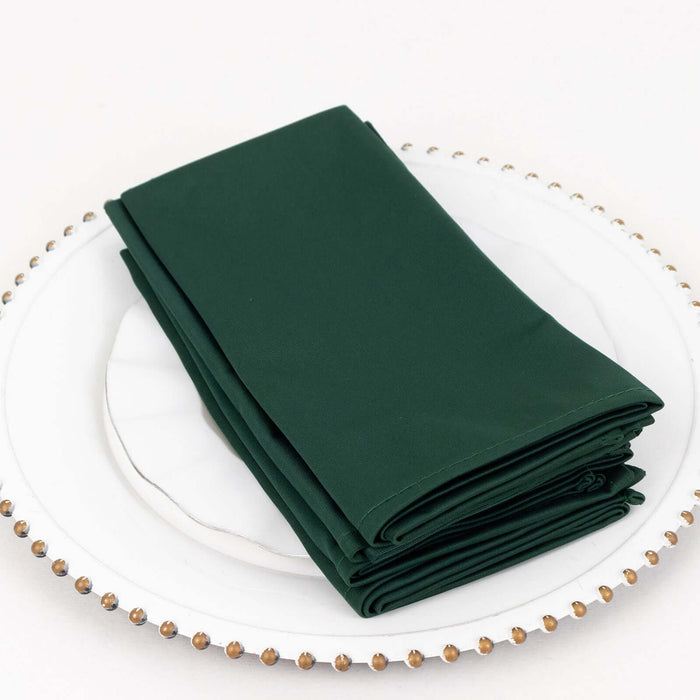Green cloth napkins neatly folded on a decorative plate.
