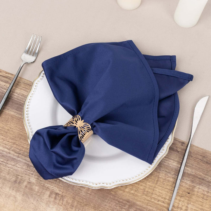 Navy blue napkin elegantly tied on a white plate with decorative cutlery.