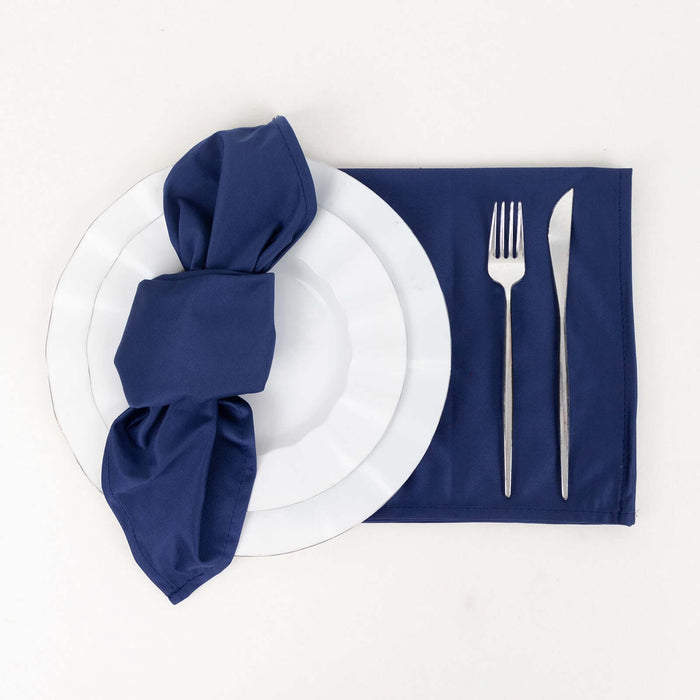 Navy napkin elegantly tied on a white plate with fork and knife on a matching mat