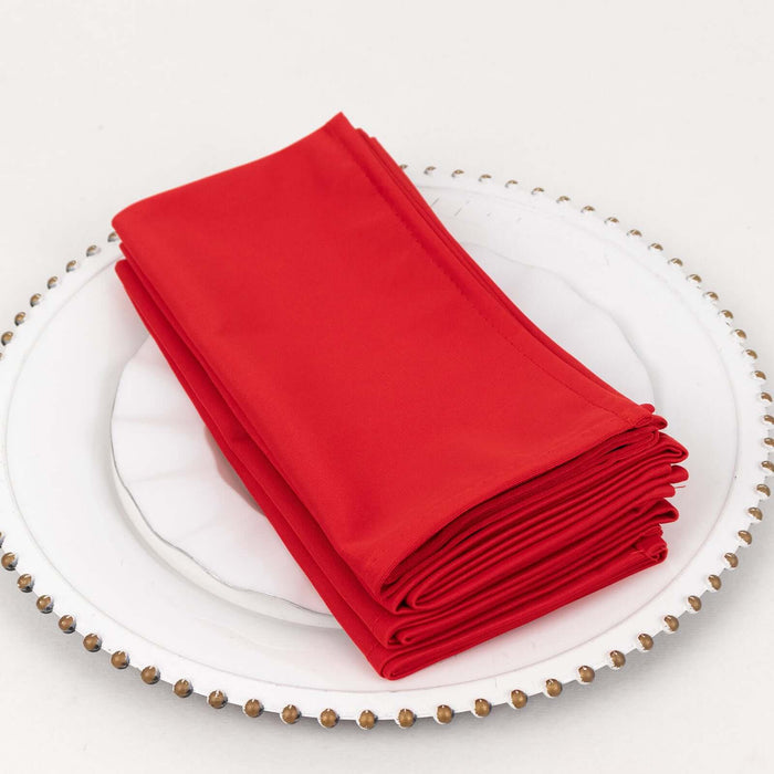 Red cloth napkins neatly stacked on a decorative plate.