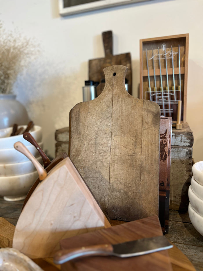 Worn antique wooden bread board with hanging hole and curved top