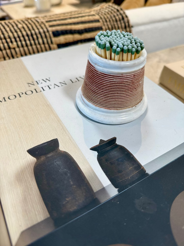 Striped porcelain match striker with matches inserted, on a dark tray
