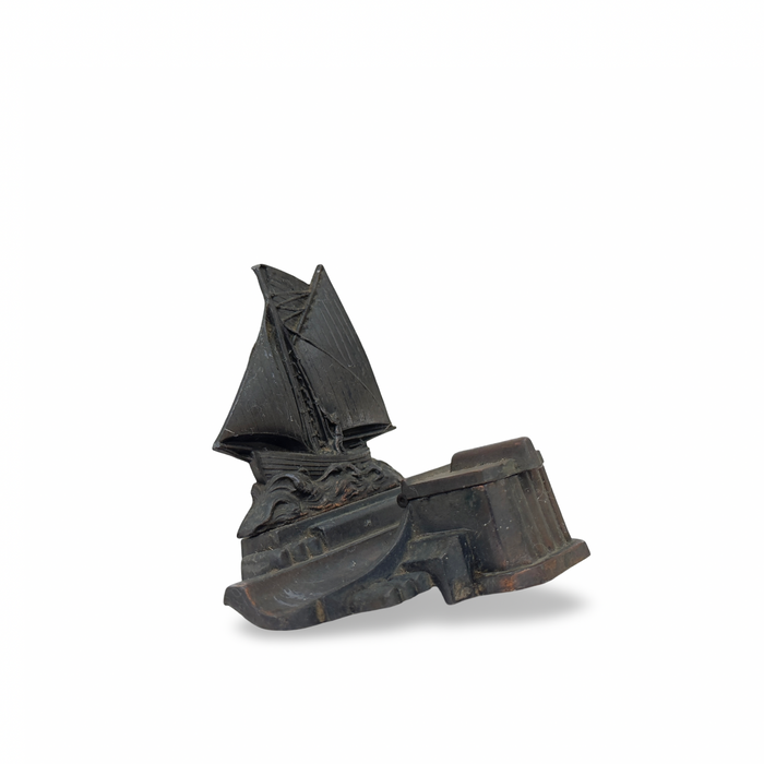 Boat-themed inkwell with sail sculpture and ribbed dark metal base, angled view