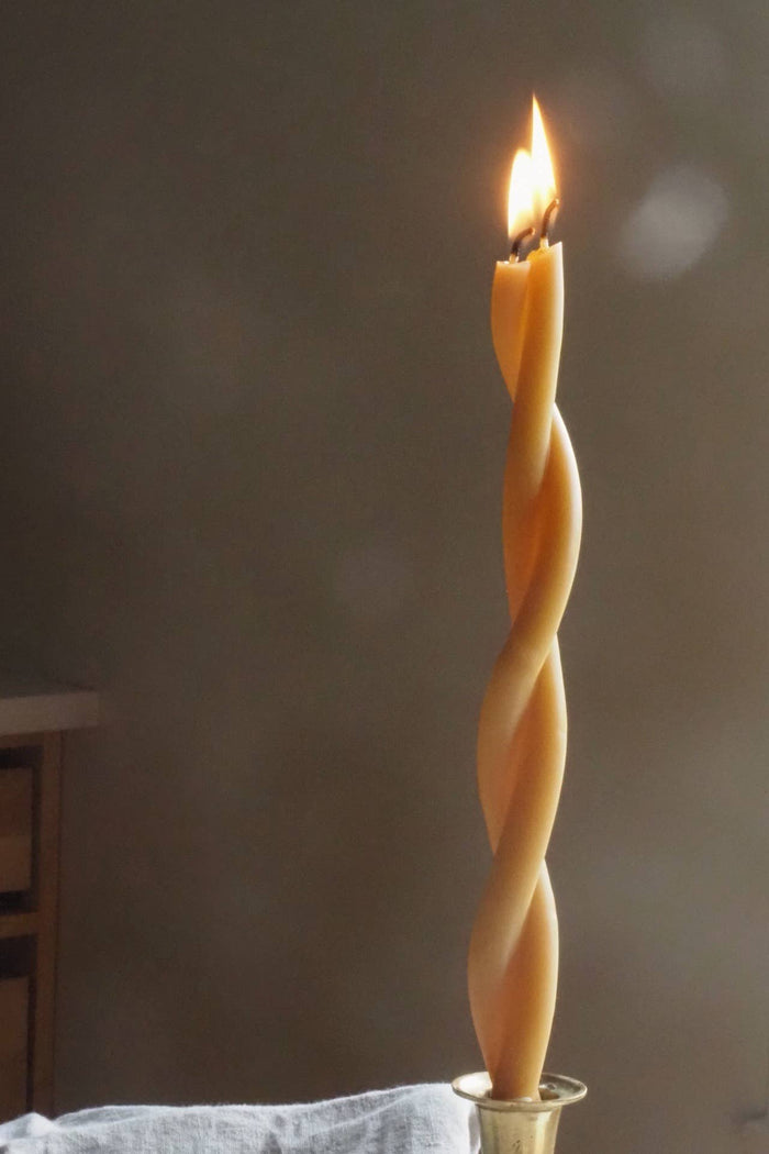 Beeswax twist taper candle, spiral wick ridges with lit top and flat metal base