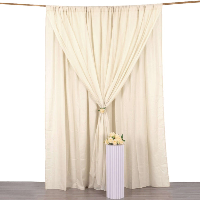 Cream colored curtain draped elegantly with flowers in a vase below.