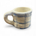 Handmade ceramic mug in off-white with blue glaze stripes, wide handle