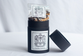 Dark chocolate toffee in a black gift cylinder with label and open lid