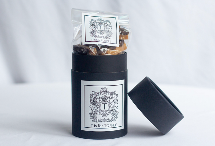 Dark chocolate toffee in a black gift cylinder with label and open lid