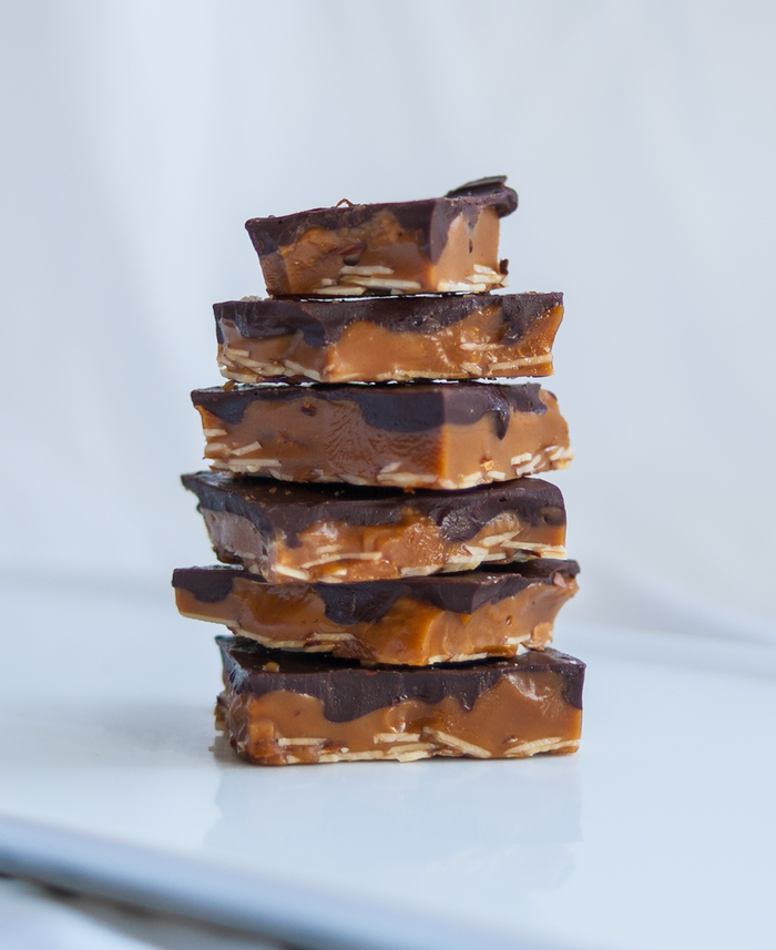 Stack of dark chocolate toffee squares with caramel filling and chocolate coating