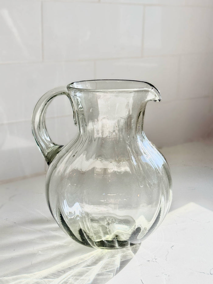 Clear glass fluted pitcher with curved handle and wide spout