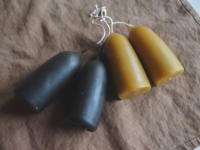 Indigo-dyed stub candles, dark and golden short shapes on a cloth