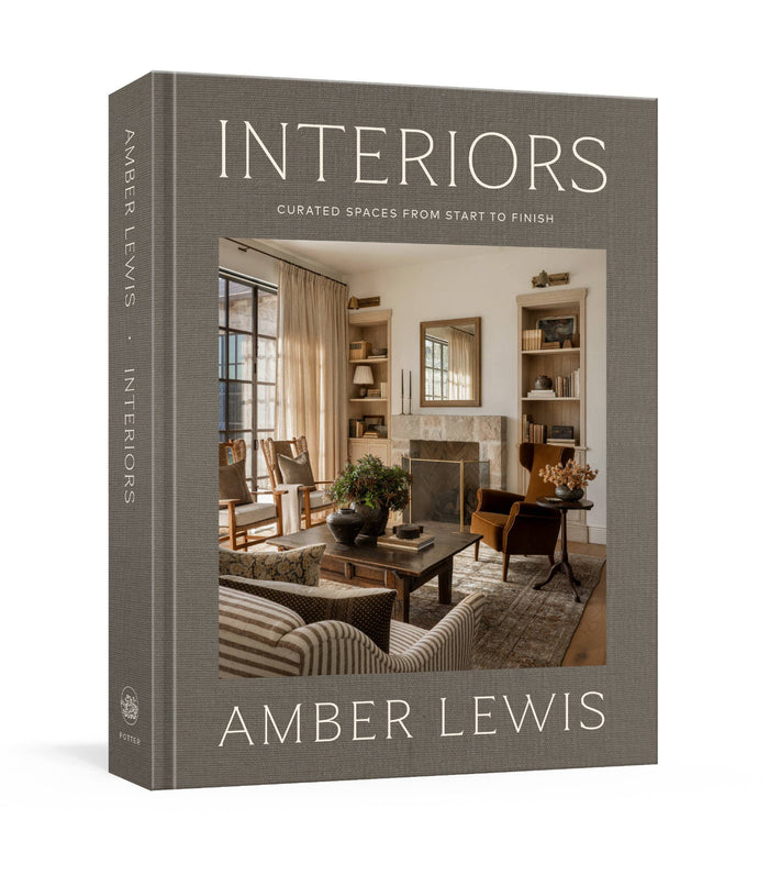 Interiors design book with “INTERIORS” title on gray hardcover, by Amber Lewis