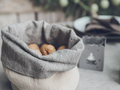 Gray striped linen storage basket with rolled rim, holding a few pinecones