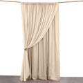 Beige curtain hanging on a rod, elegantly draped with a tieback.
