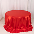 Red round tablecloth with elegant draping and a glossy finish.