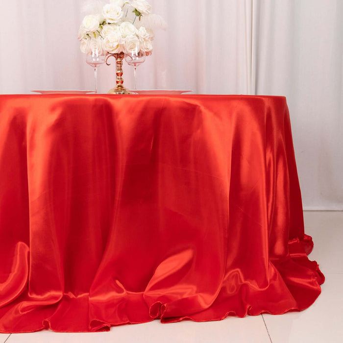 Red satin tablecloth draped elegantly over a table with floral centerpiece.