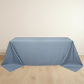 Blue tablecloth draped over a table on a light wooden floor.