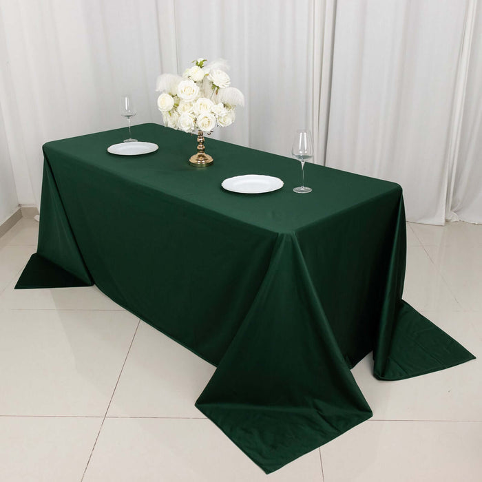 Elegant green tablecloth set with white plates and a floral centerpiece.