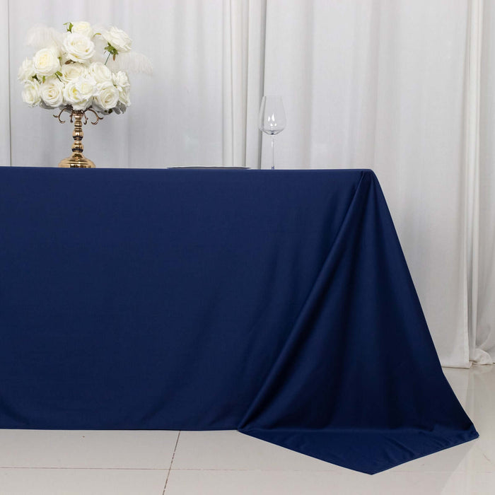Navy tablecloth draped elegantly on a table with white roses and a glass.
