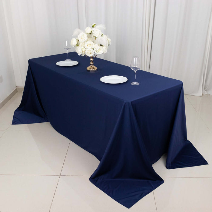 Navy blue tablecloth on a dining table with white plates and a floral centerpiece.