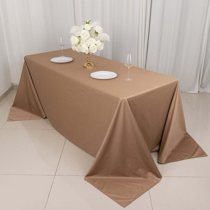 Elegant brown tablecloth set with white plates and floral centerpiece.