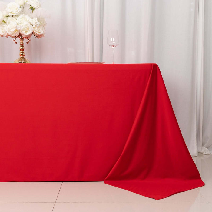 Red tablecloth draped elegantly over a table with floral arrangement and glass.