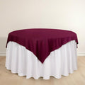 Round table with a burgundy tablecloth and white skirt.