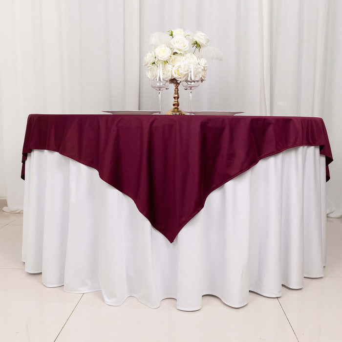 Elegant burgundy tablecloth draped over a white table with floral centerpiece.