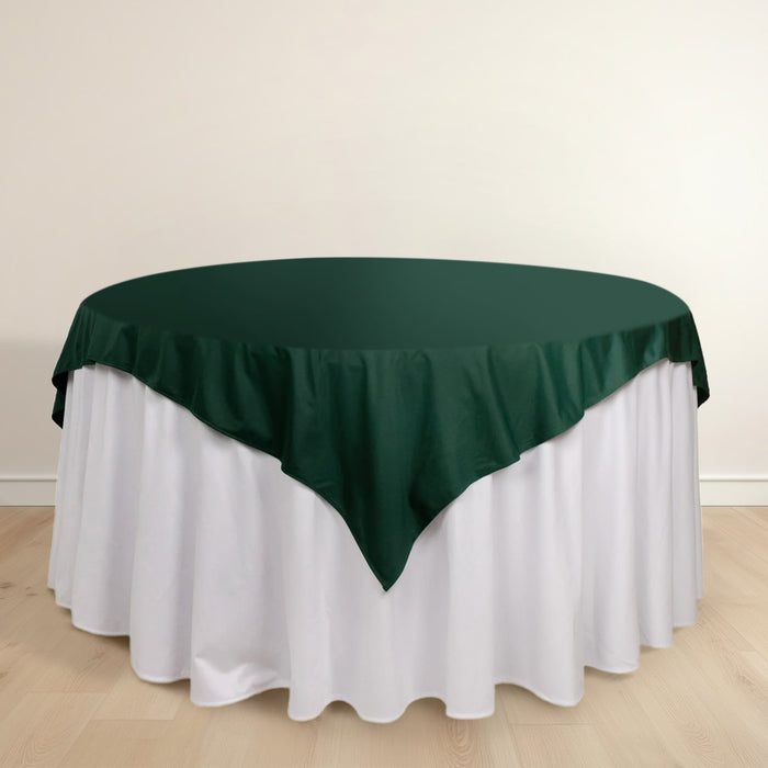 Green tablecloth draped over a round table with a white skirt.