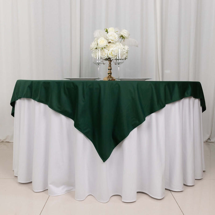 Green tablecloth draped over a round table with a floral centerpiece.
