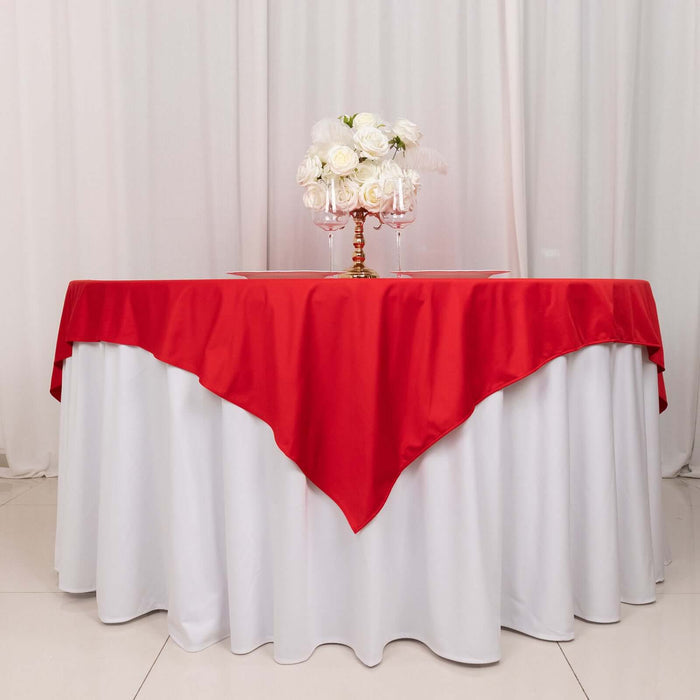 Red tablecloth draped elegantly over a white table with floral centerpiece.