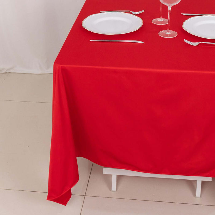 Red tablecloth draped over a white table with plates and glassware.