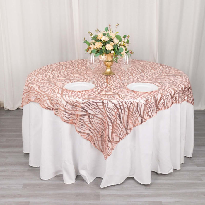Rose gold patterned table overlay on a round white table with floral centerpiece.