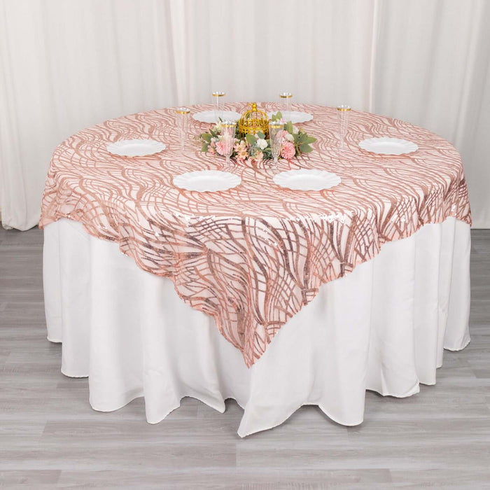 Round table with a pink and white patterned tablecloth and floral centerpiece.
