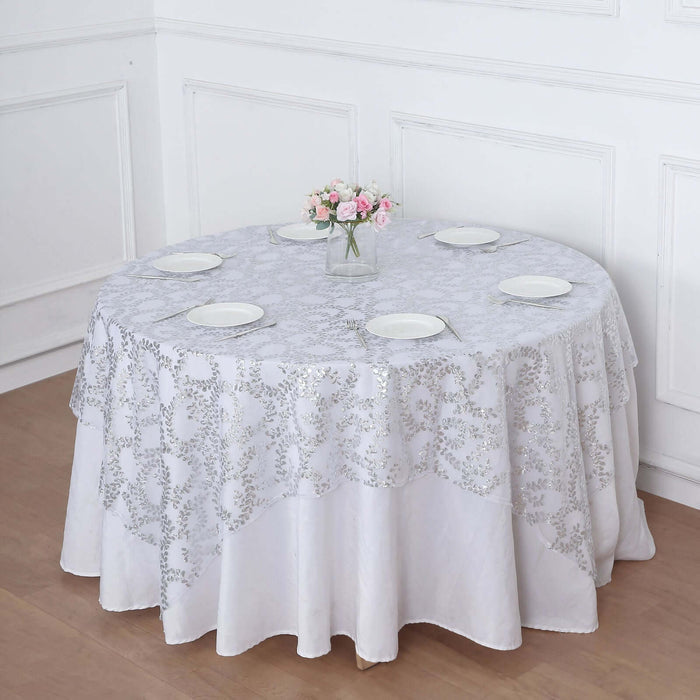 Round table with a white lace tablecloth and flower vase centerpiece.