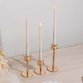 Elegant gold candle holders with white taper candles on a wooden surface.