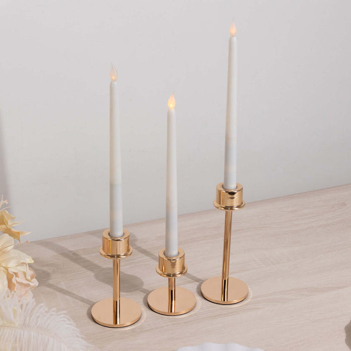 Elegant gold candle holders with white taper candles on a wooden surface.
