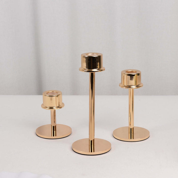 Set of three gold candle holders in varying heights on a white background.
