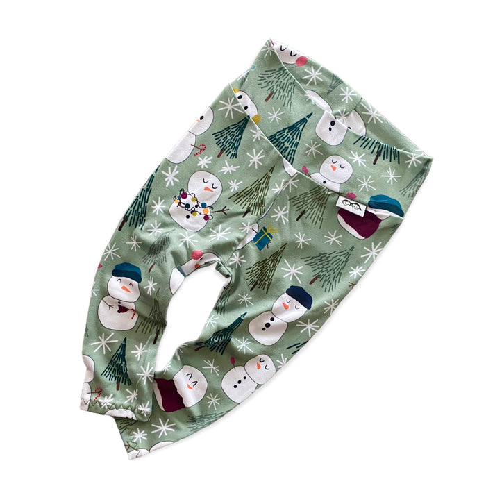 Snowman Print Lounge Set featuring a long-sleeve pullover and matching leggings with a playful snowman and winter tree design on a soft green background. Handmade for babies and toddlers, perfect for holiday celebrations and seasonal wear.