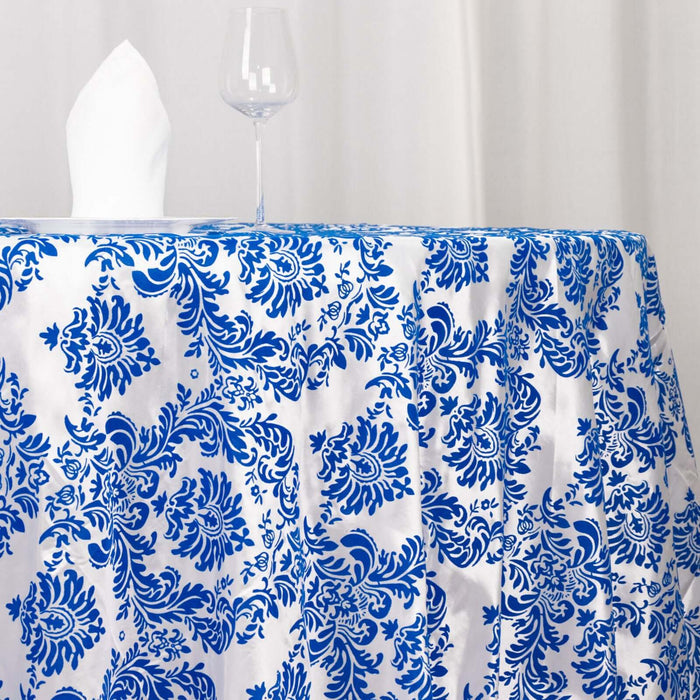 Blue and white patterned tablecloth draped over a table with a glass and napkin.
