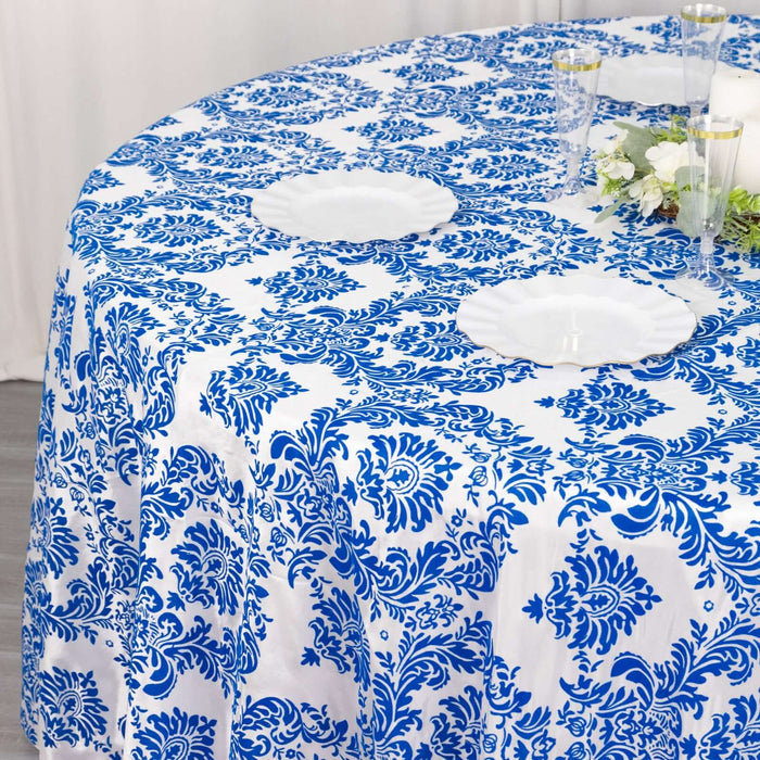 Blue and white floral tablecloth on a round table with plates and glasses.
